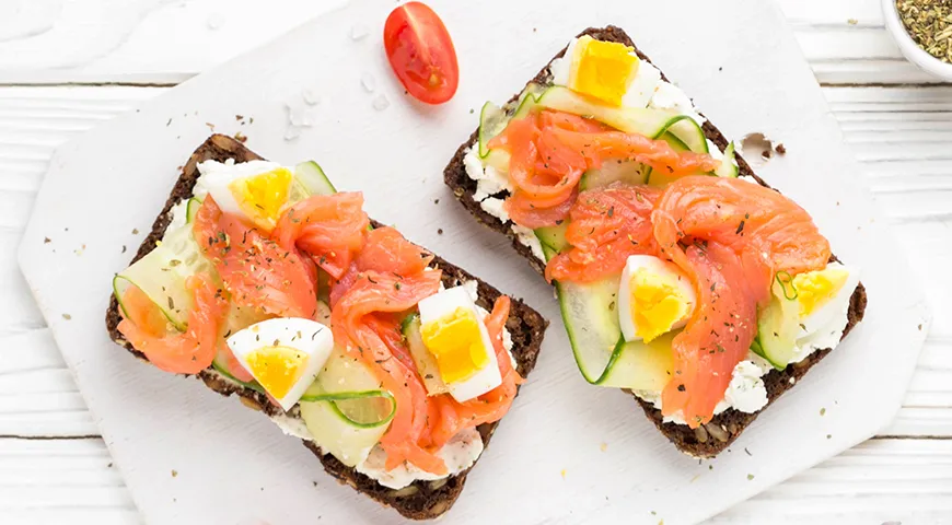 Sandwiches mit rotem Fisch, Gurke und Ei auf Schwarzbrot mit Kernen sehen sehr elegant aus