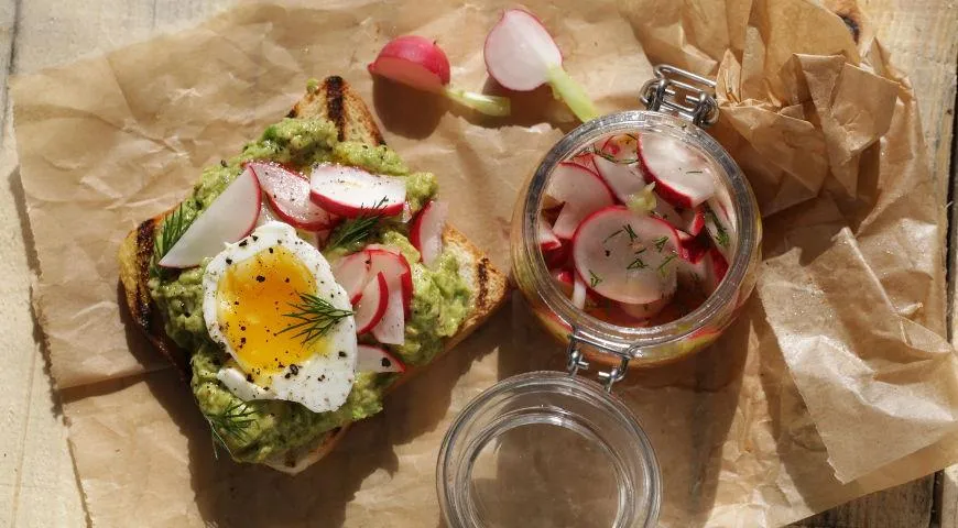 Toast mit eingelegten Radieschen, Avocado und Eiern in einer Tüte