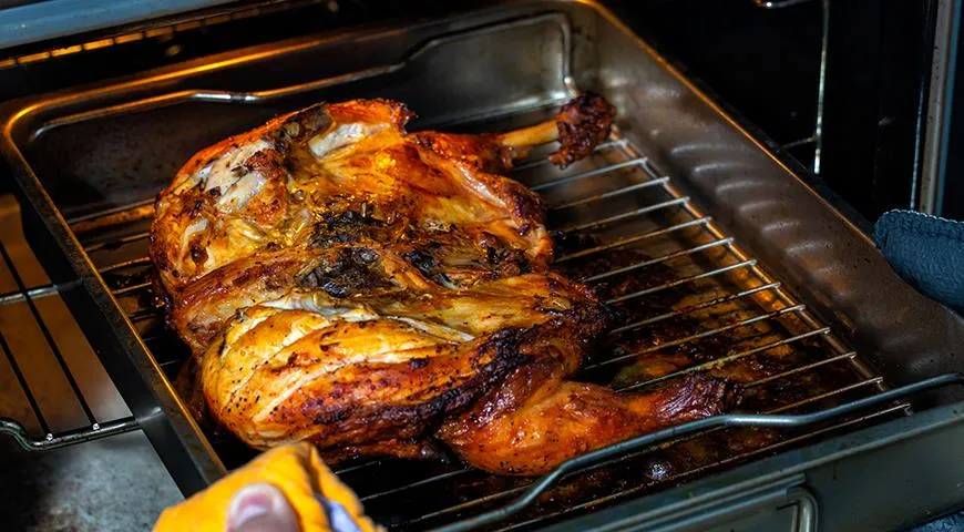 Um sicherzustellen, dass das Hähnchen gleichmäßig backt, schneiden Sie den Kadaver entlang des Grats ein, legen Sie ihn auf ein Backblech und drücken Sie ihn im Brustbereich mit der Hand fest