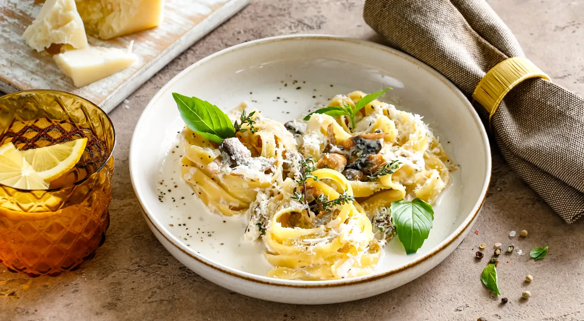 Nester mit Pilzen und Käse in Sahnesauce in einer Pfanne erhitzen