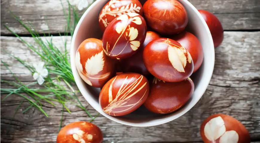 Mit Zwiebelschalen bemalte Eier mit zusätzlicher Dekoration